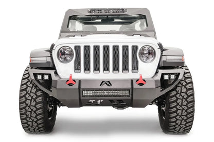 Fab Fours Vengeance front bumper on a white Jeep Wrangler JL, straight-on front view, showing the angular bumper, center LED light bar, cube lights and red tow hooks