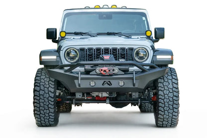 Fab Fours Premium front Lifestyle bumper with pre-runner guard on a white Jeep Wrangler JL on a gravel road, straight-on front view, showing the tube hoop, winch with red hook and round lights