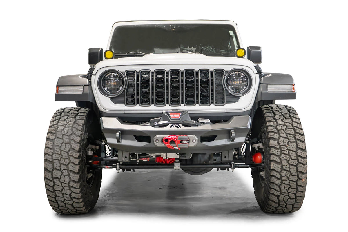 Fab Fours Ghost stubby front winch bumper with no guard on a white Jeep Wrangler JL, straight-on front view, showing the centered winch and fairlead, Fab Fours logo and D-ring mounts
