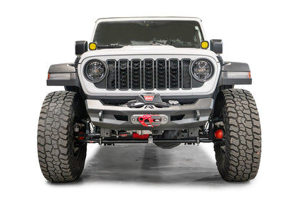 Fab Fours Ghost stubby front winch bumper with no guard on a white Jeep Wrangler JL, straight-on front view, showing the centered winch and fairlead, Fab Fours logo and D-ring mounts