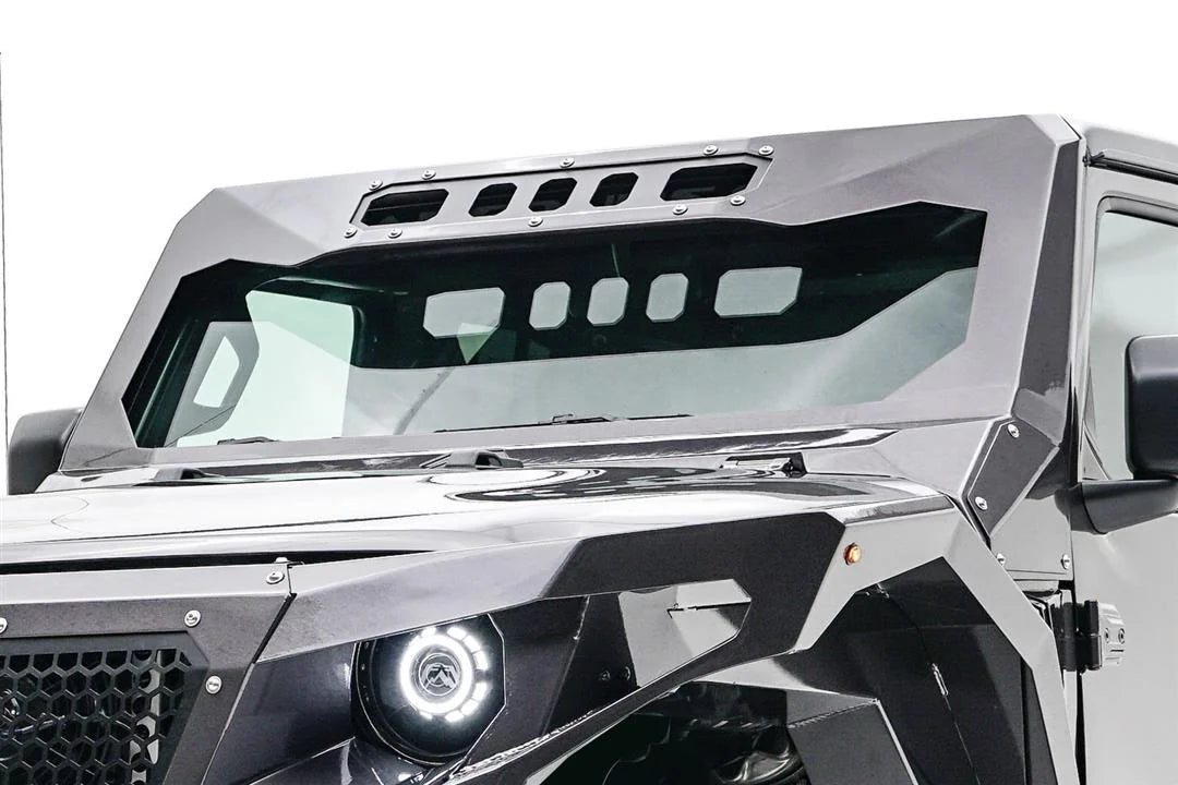 Close-up of the Fab Fours ViCowl on a Jeep Wrangler JL, driver side, showing the formed steel cowl wrapping the windshield frame with a slotted visor and bolted A-pillar cover