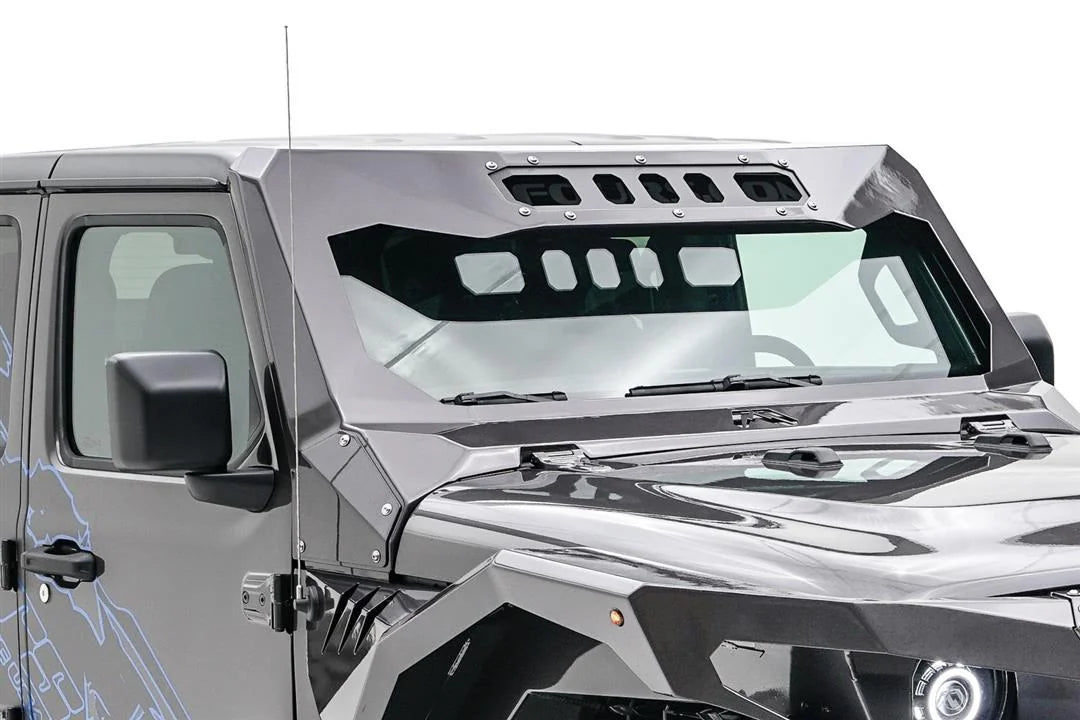 Close-up of the Fab Fours ViCowl on a gray Jeep Wrangler JL, passenger side, showing the angular steel A-pillar cover, slotted visor panel and retained factory antenna