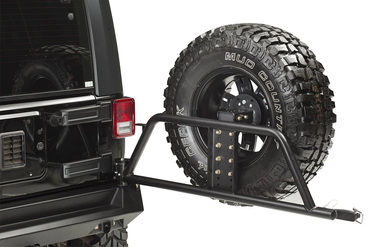 Fab Fours Swing-Away Tire Carrier on a black Jeep Wrangler JK, swung open to show the tubular arm, adjustable tire mount plate and latch