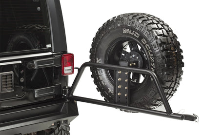 Fab Fours Swing-Away Tire Carrier on a black Jeep Wrangler JK, swung open to show the tubular arm, adjustable tire mount plate and latch