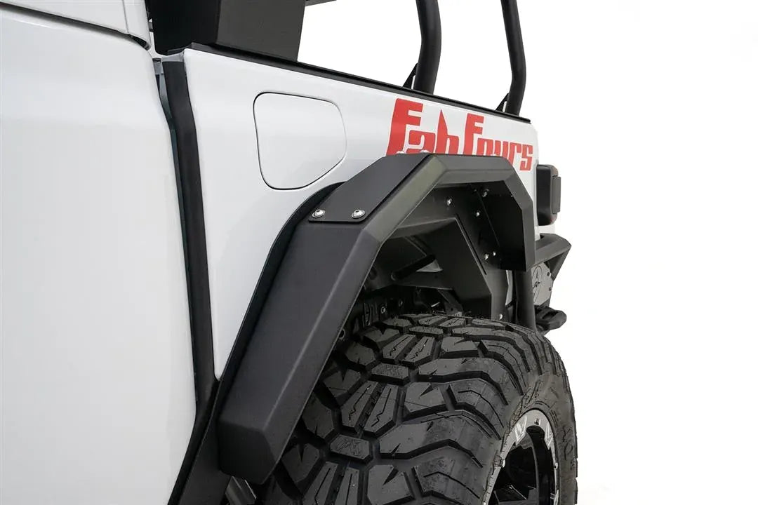 Close-up of Fab Fours rear fender flare on the driver side of a white Jeep Gladiator near the fuel door, with red Fab Fours graphics