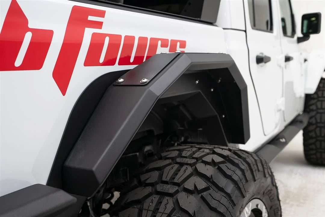 Close-up of Fab Fours rear fender flare on the passenger side of a white Jeep Gladiator with red Fab Fours graphics, with mud-terrain tire