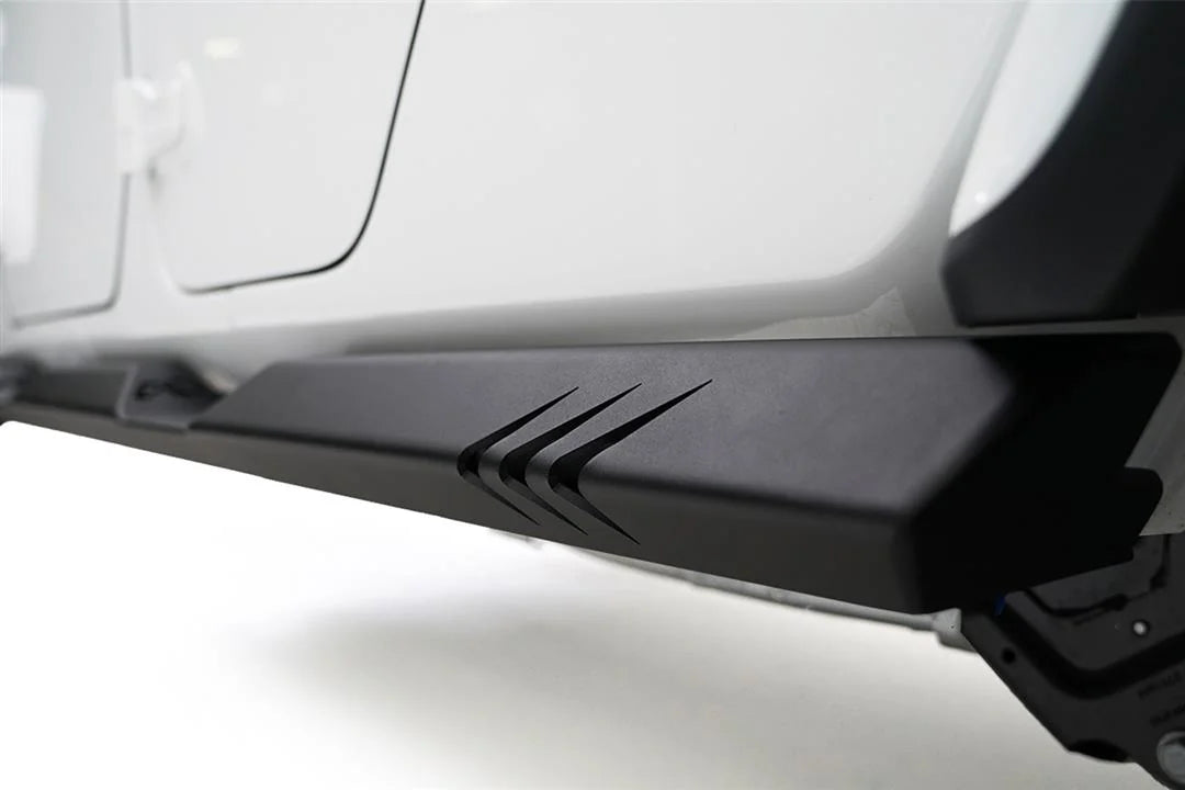 Close-up of the Fab Fours rock slider end on a Jeep Gladiator, showing the chevron cutout design and textured matte black finish