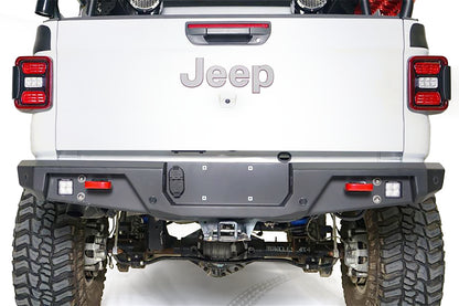Close-up of Fab Fours standard rear bumper on a white Jeep Gladiator, straight rear view, with cube lights, red recovery points, parking sensors, and center license plate mount
