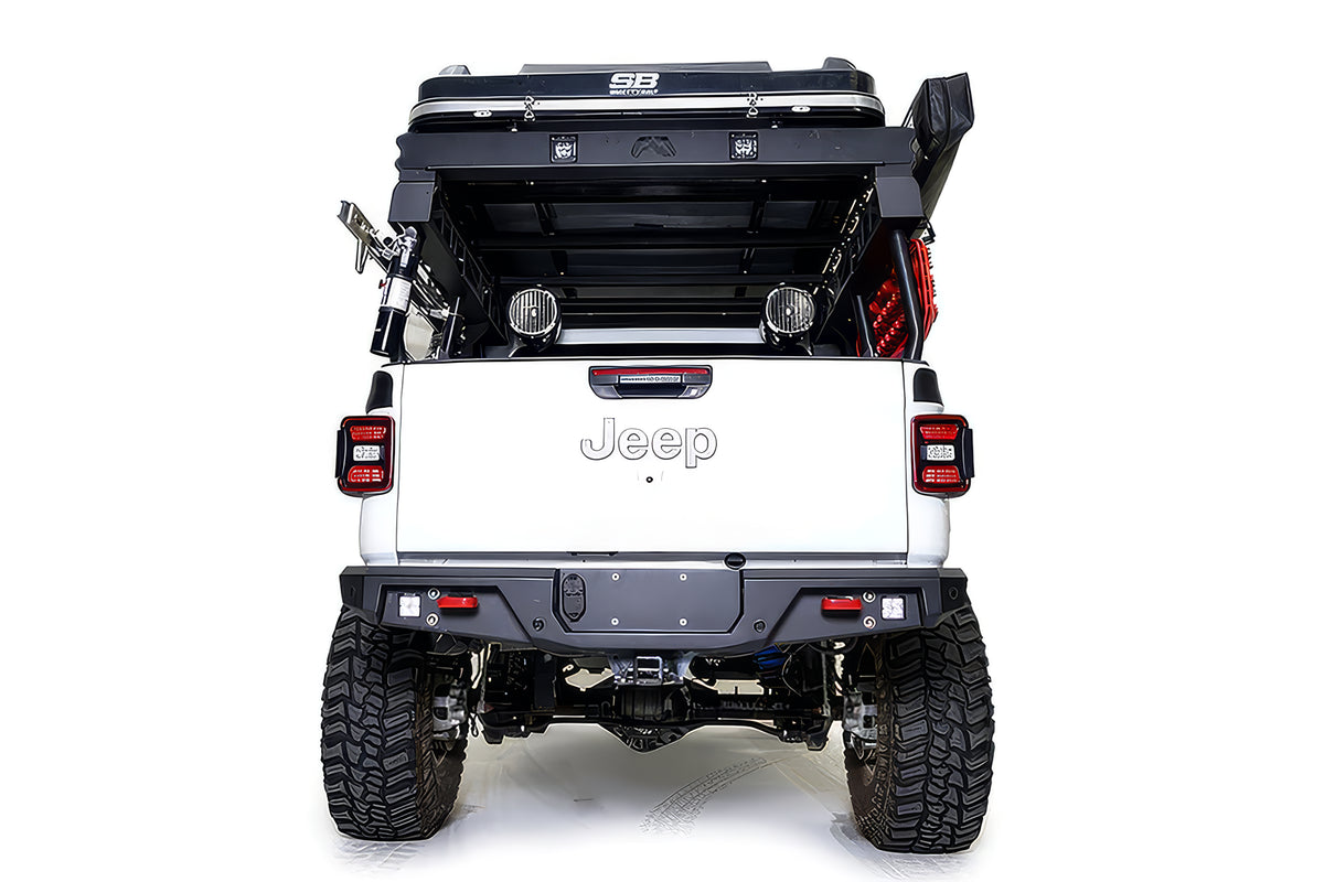 Fab Fours standard rear bumper on a lifted white Jeep Gladiator with overland bed rack, straight rear view, with cube lights, red recovery points, and hitch receiver
