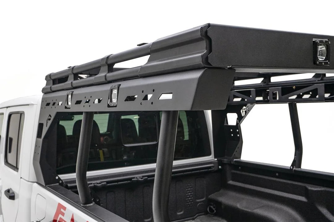 Close-up of the Fab Fours Overland Bed Rack driver-side rail on a white Jeep Gladiator, showing the slotted mounting panel, integrated cube lights and tubular uprights