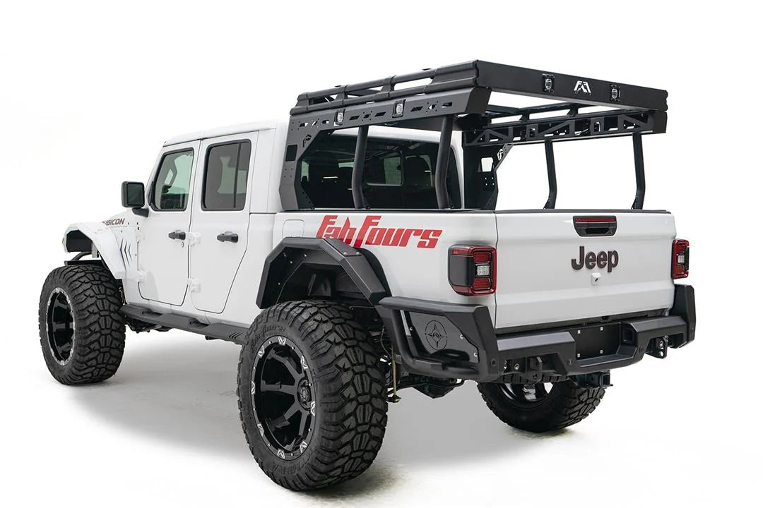 Fab Fours Overland Bed Rack on a white Jeep Gladiator Rubicon, rear driver-side view, showing the black platform, cross-braced side frames and tubular uprights mounted over the bed