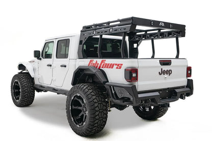 Fab Fours Overland Bed Rack on a white Jeep Gladiator Rubicon, rear driver-side view, showing the black platform, cross-braced side frames and tubular uprights mounted over the bed