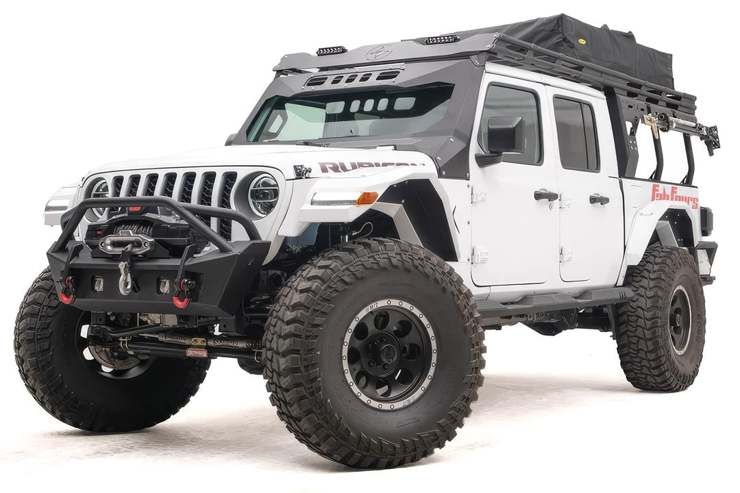 Fab Fours Overland Rack extension on a white Jeep Gladiator Rubicon, front driver-side view, with the black roof rack running from the windshield back over the bed and a rooftop tent on top