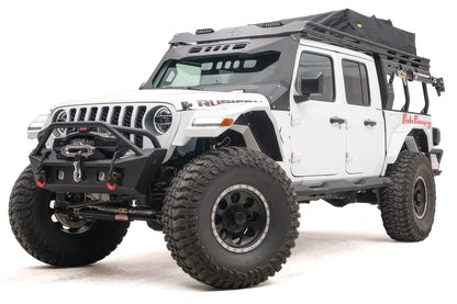 Fab Fours Overland Rack extension on a white Jeep Gladiator Rubicon, front driver-side view, with the black roof rack running from the windshield back over the bed and a rooftop tent on top