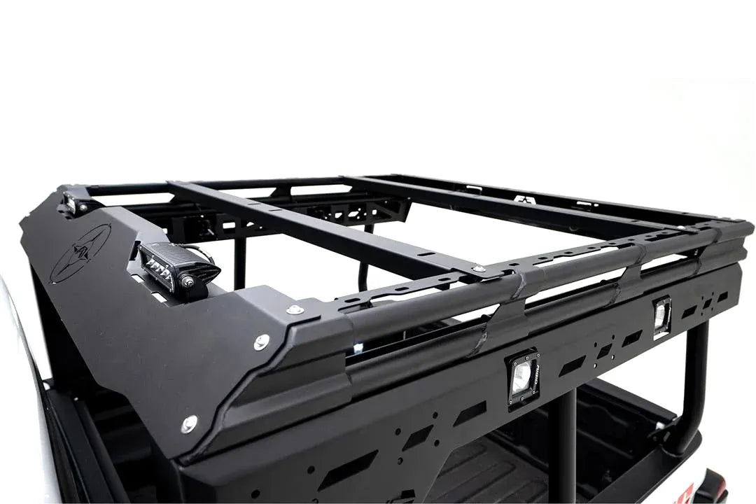 Fab Fours Overland Rack additional crossmembers on a white Jeep Gladiator, elevated driver-side view, with black crossbars across the platform behind the logo-cut front fairing and RIGID lights