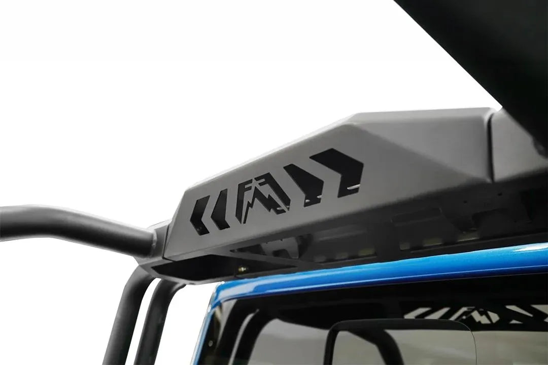 Close-up of the Fab Fours sport rack center panel with Fab Fours logo and chevron cutouts behind the cab of a blue Jeep Gladiator