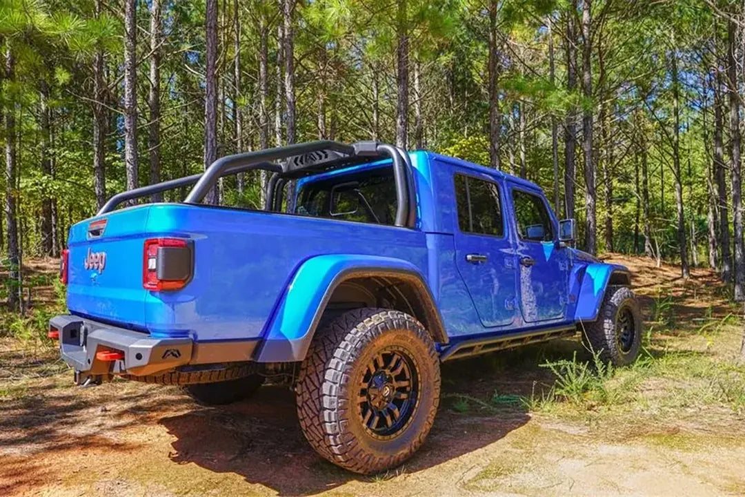 Fab Fours sport rack on a lifted blue Jeep Gladiator Rubicon in the woods, passenger-side rear three-quarter view, with Fab Fours rear bumper