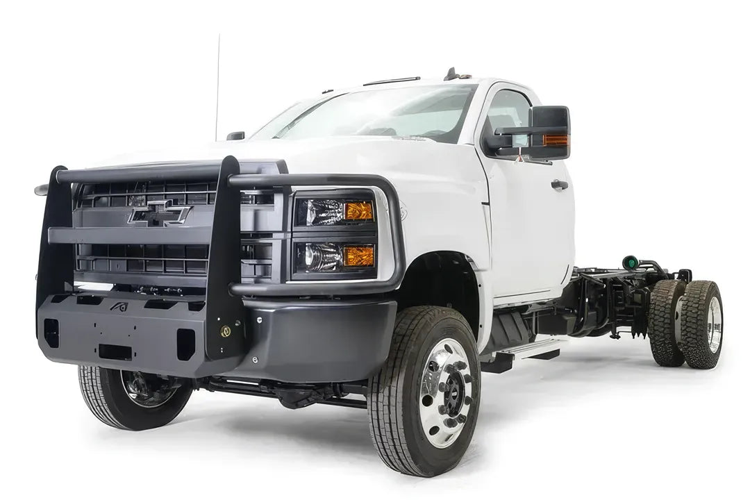Fab Fours winch mount with full guard on a white Chevrolet Silverado 4500 chassis cab, driver-side front three-quarter view, showing the full grille guard, headlight hoops and winch plate