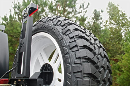 Fab Fours third brake light on a Jeep Wrangler JK, raised on a black bracket above the spare tire, shown outdoors