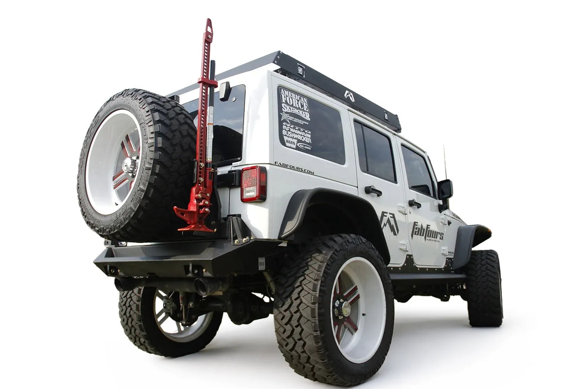 Fab Fours Hi-Lift jack mount on a white Jeep Wrangler JK outdoors, rear passenger-side three-quarter view, showing the jack mounted on the tire carrier, spare tire and rear bumper