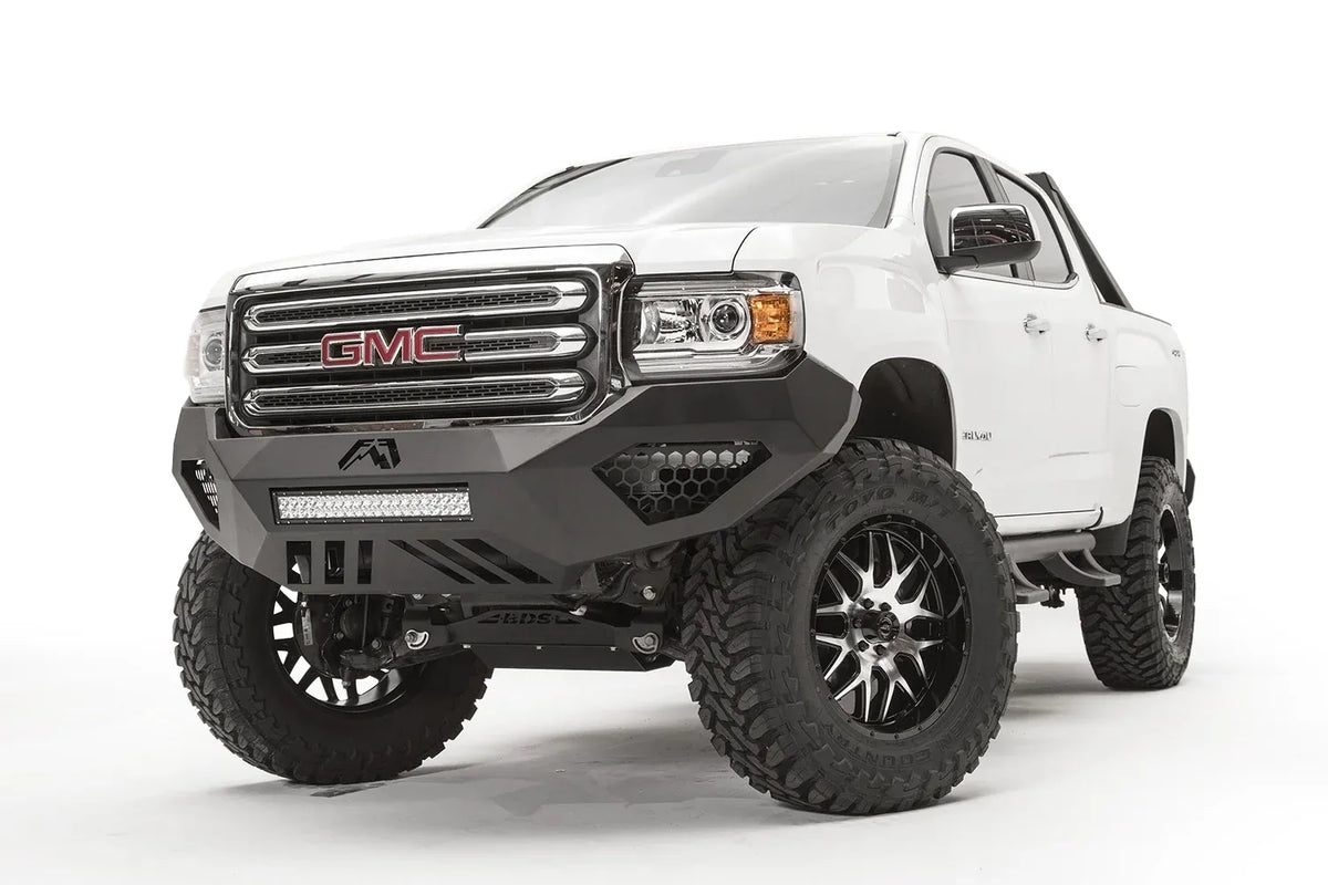 Black honeycomb mesh insert covers in the side light openings of a Fab Fours Vengeance front bumper on a lifted white GMC Canyon, driver-side front three-quarter view