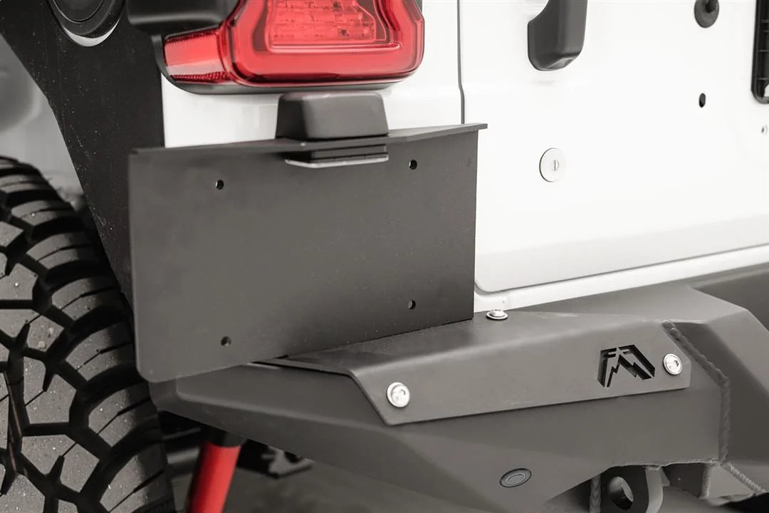 Close-up of Fab Fours license plate bracket mounted on the driver-side corner of a Fab Fours rear bumper on a white Jeep Wrangler JL