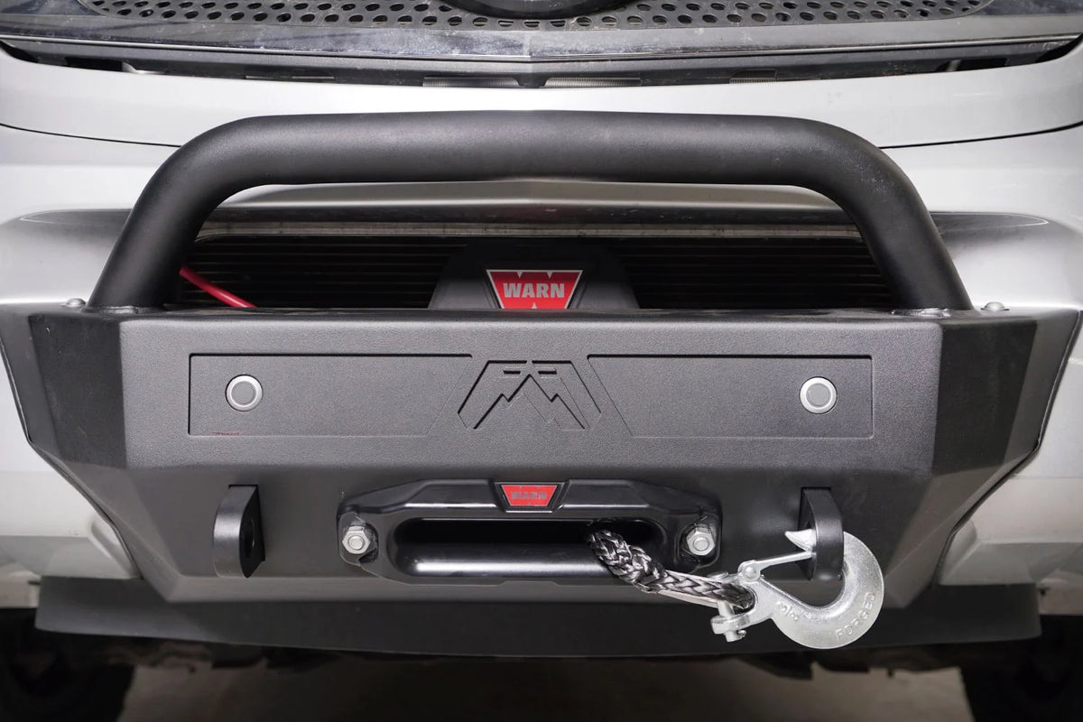 Fab Fours sensor plate with two parking sensors and Fab Fours logo mounted on a front bumper with pre-runner guard and Warn winch, straight-on view