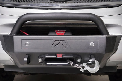 Fab Fours sensor plate with two parking sensors and Fab Fours logo mounted on a front bumper with pre-runner guard and Warn winch, straight-on view