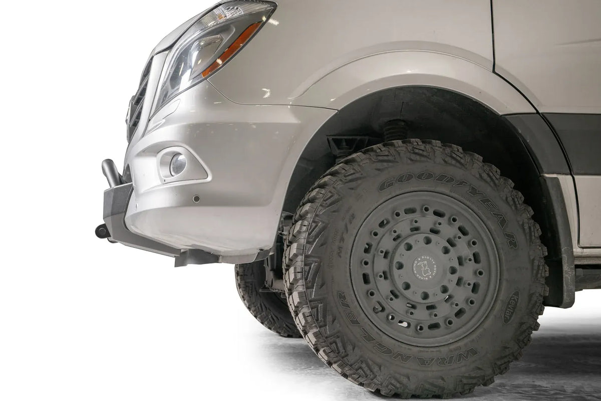 Fab Fours semi-hidden winch mount on a silver Mercedes-Benz Sprinter, close-up of the front corner, showing the mount's side profile and clearance to the front wheel