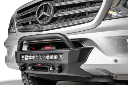 Fab Fours semi-hidden winch mount with pre-runner guard on a silver Mercedes-Benz Sprinter, close-up angle, showing the tube hoop, winch, light bar and fairlead