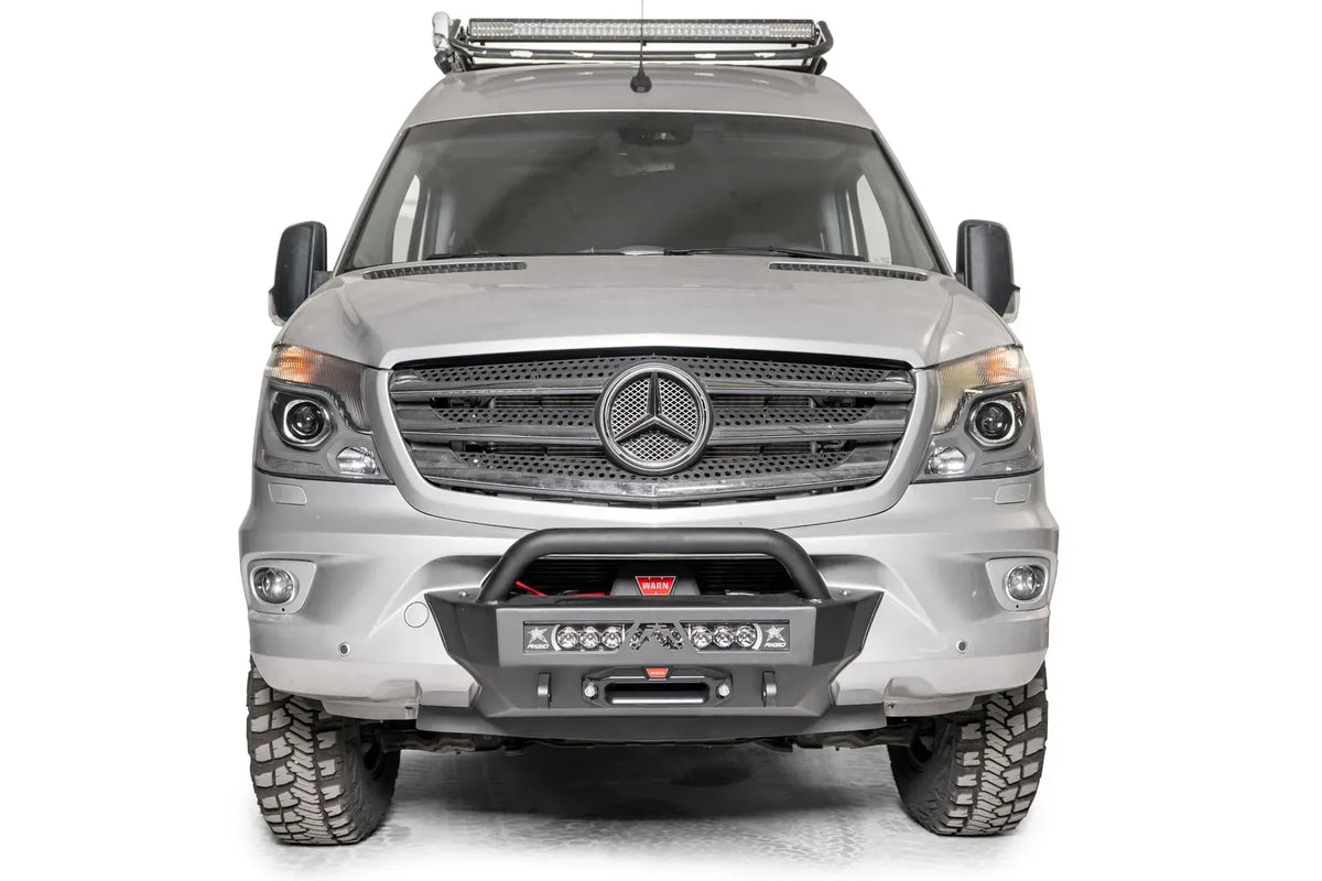 Fab Fours semi-hidden winch mount with pre-runner guard on a silver Mercedes-Benz Sprinter, straight-on front view, showing the tube hoop, light bar and fairlead