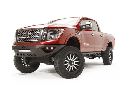 Fab Fours Vengeance front bumper on a red Nissan TITAN XD, driver-side front three-quarter view, showing the angular bumper, LED light bar and skid plate