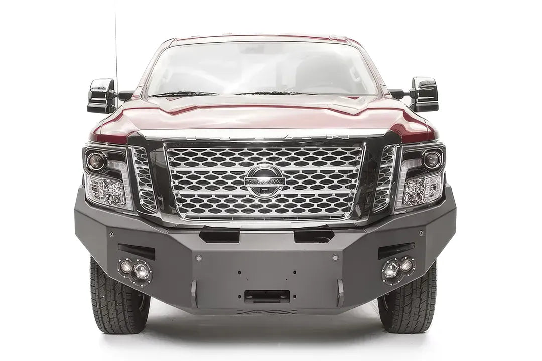 Fab Fours Premium front bumper on a red Nissan TITAN XD, straight-on front view, showing the full-width bumper, centered winch opening and round fog lights