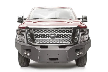 Fab Fours Premium front bumper on a red Nissan TITAN XD, straight-on front view, showing the full-width bumper, centered winch opening and round fog lights