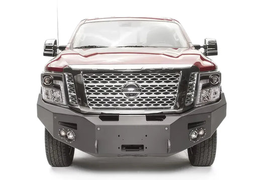 Fab Fours Premium front bumper on a red Nissan TITAN XD, straight-on front view, showing the full-width bumper, centered winch opening and round fog lights