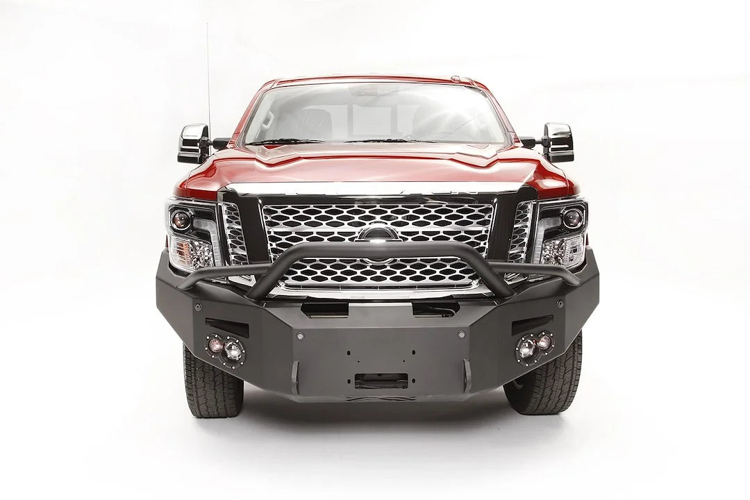 Fab Fours Premium front bumper with pre-runner guard on a red Nissan TITAN XD, straight-on front view, showing the tube hoop, centered winch opening and round fog lights