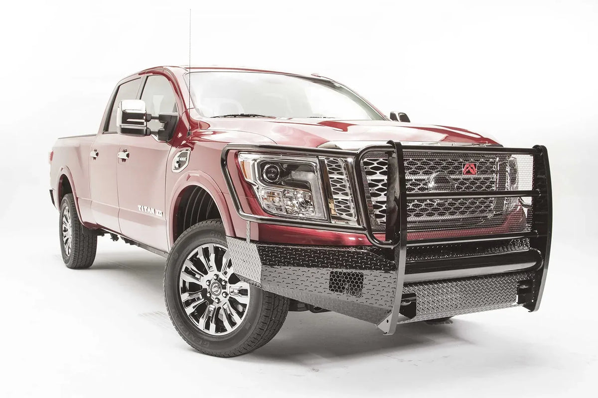 Fab Fours Black Steel front bumper with full guard on a red Nissan TITAN XD, passenger-side front three-quarter view, showing the full grille guard, diamond-plate bumper and headlight hoops