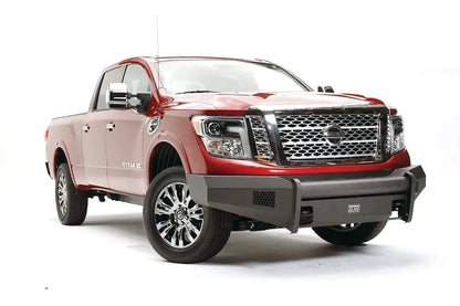 Fab Fours Black Steel Elite front bumper on a red Nissan TITAN XD, driver-side front three-quarter view, showing the smooth steel bumper, mesh light openings and Elite badge