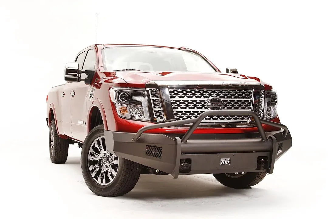 Fab Fours Black Steel Elite front bumper with pre-runner guard on a red Nissan TITAN XD, driver-side front three-quarter view, showing the tube hoop, mesh light openings and Elite badge