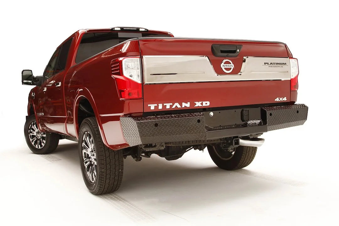 Fab Fours Black Steel Ranch rear bumper with diamond plate on a red Nissan Titan XD, driver-side rear three-quarter view, with center license plate area and hitch receiver