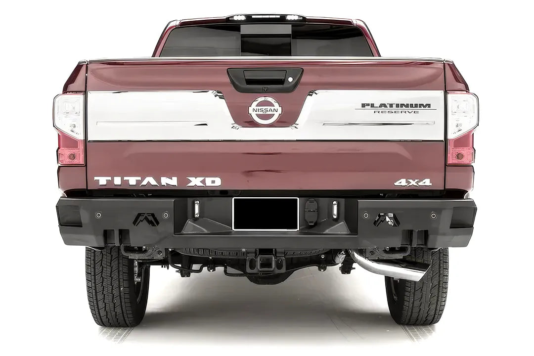 Fab Fours Premium rear bumper on a red Nissan Titan XD, straight rear view, with parking sensors, center license plate area, Fab Fours logo cutouts, and hitch receiver