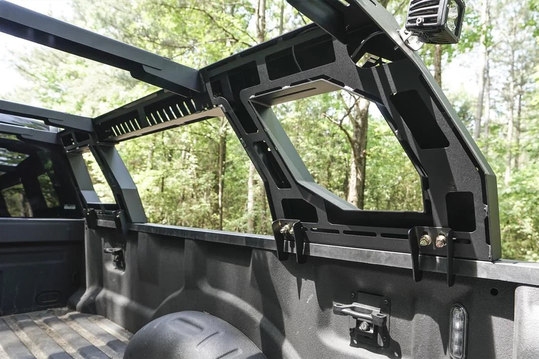Close-up of the Fab Fours Adjustable Overland Rack inside a truck bed, showing the bed rail clamp mounts, cutout side panel and vented crossbar