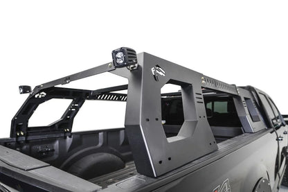 ab Fours Adjustable Overland Rack in a black full-size pickup bed, rear passenger-side view, showing the matte black side panels with Fab Fours logo cutouts, vented crossbars and RIGID cube lights