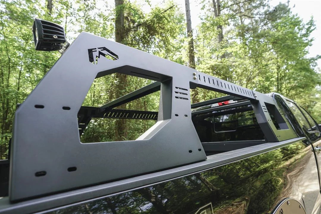 Close-up of the Fab Fours Adjustable Overland Rack side panel on a black pickup, showing the large cutout window, slotted mounting points and vented crossbars