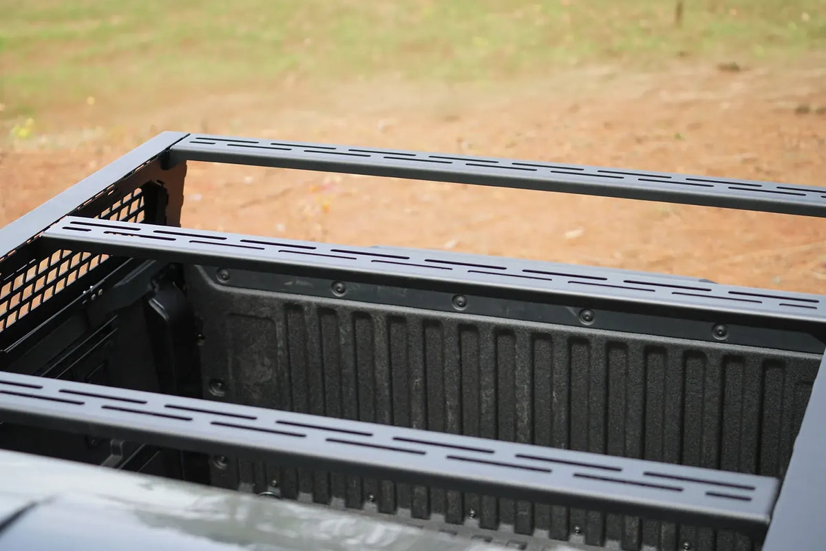 Close-up of slotted crossbars on a Fab Fours half rack over the bed of a Toyota Tacoma