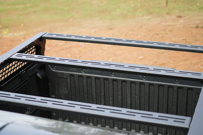 Close-up of slotted crossbars on a Fab Fours half rack over the bed of a Toyota Tacoma