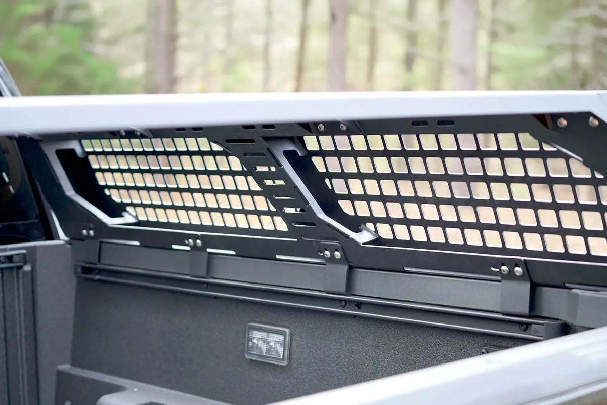 Close-up of the Fab Fours half rack mesh panel and mounting rail inside the bed of a Toyota Tacoma