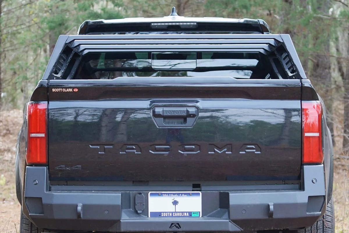 Fab Fours half rack on a black Toyota Tacoma, straight rear view over the tailgate, with Fab Fours rear bumper