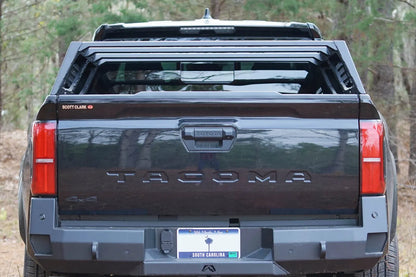 Fab Fours half rack on a black Toyota Tacoma, straight rear view over the tailgate, with Fab Fours rear bumper
