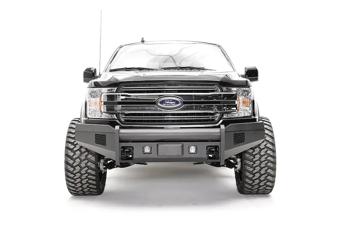 Fab Fours Elite adaptive cruise control relocation bracket on a black Ford F-150, straight-on front view, showing the centered sensor plate in an Elite bumper without guard